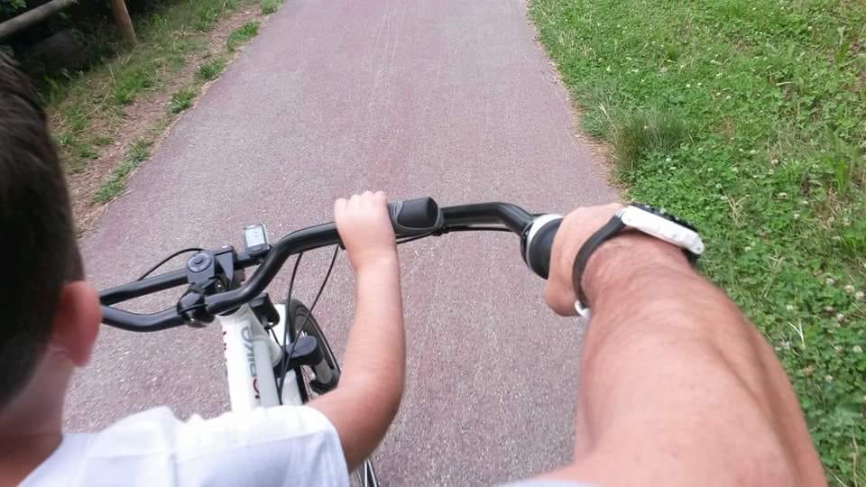 Padre e figlio in strada su un tandem, visuale in prima persona